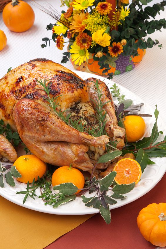 14065409 - garnished citrus glazed roasted turkey on holiday table, pumpkins, flowers, and white wine